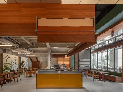 Interior view of a modern restaurant/cafe with wood accents and open seating areas.