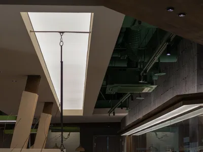 Modern interior design of a restaurant with a green screen counter and contemporary materials.