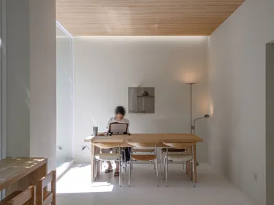 A minimalist home office with a wooden desk and chairs.
