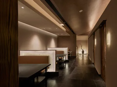 A minimalist restaurant interior featuring stone, leather, and wood materials.