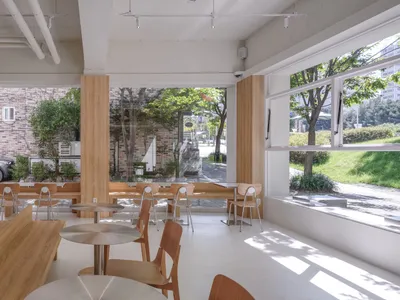 A modern restaurant interior with wooden furniture, tables, and seating.