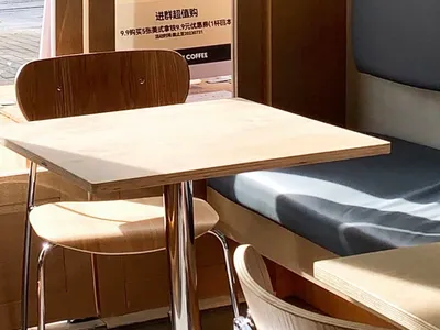 A cafe interior with wooden furniture and a promotional poster