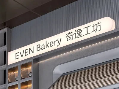Even Bakery storefront with illuminated signage featuring metallic elements.