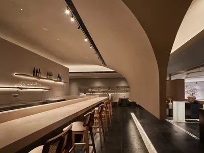 A modern restaurant bar with a concrete counter and barstools