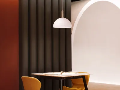 A minimalist restaurant interior featuring metal and leather elements, including chairs, table, and lamp.