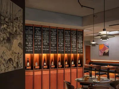 A modern restaurant dining room featuring wooden tables, glass walls, and metal chairs.