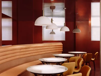 A modern restaurant interior with marble tables and a leather seating area.
