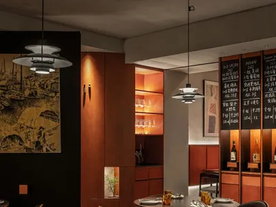 燈光充足的現代餐廳室內，配有木製餐桌、黑色皮革椅以及工業風格燈具。