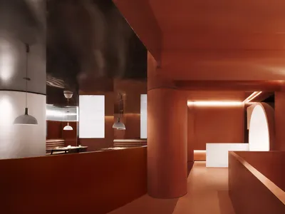 Modern restaurant interior with exposed concrete walls and white pendant lights.