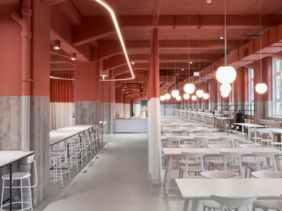A spacious, industrial-style restaurant interior with concrete flooring and minimalist design features.