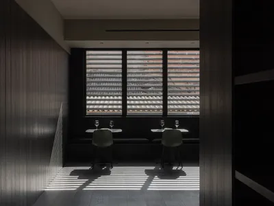 Interior of a modern restaurant with dark accents, featuring minimalist design and wooden materials.