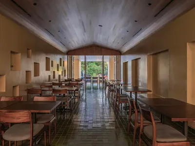 現代餐廳室內，木質餐桌椅、混凝土牆面與挑高天花板。
