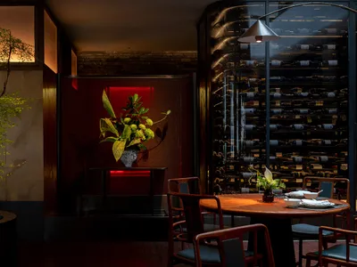 A modern restaurant interior with wooden furniture, glass shelving, and metal accents.