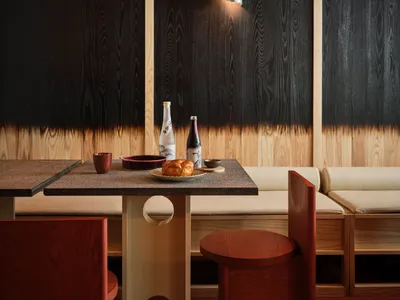 A modern restaurant interior with a wooden table and chairs, featuring a sleek design and minimalist aesthetics.