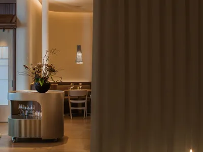 Modern restaurant interior with white curtains and wooden flooring.