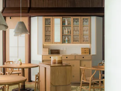 A modern restaurant interior with wooden furniture and a central bar area.