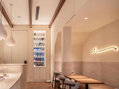 A minimalist cafe interior with white marble countertops, concrete walls, and fabric seating.