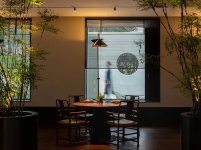 A modern restaurant interior with wooden furniture and plants.