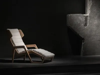 A minimalist chaise lounge with white fabric upholstery in a dark room setting.