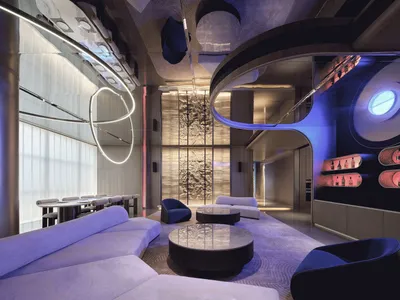 Modern lounge area with glass walls, metal accents, and upholstered furniture.