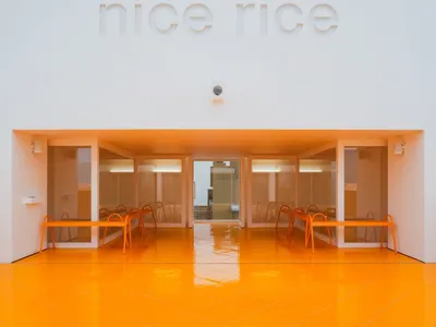 The entrance of a minimalist restaurant featuring glass walls and tables.