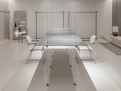 A sleek, minimalist restaurant interior with a polished concrete dining area featuring a long, rectangular table and contempo