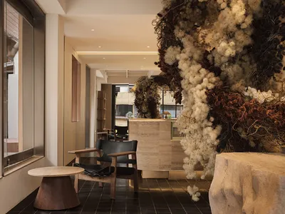 A hotel reception area featuring modern decor with dry flower arrangements, concrete elements, and comfortable seating.