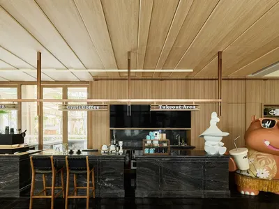 A modern bar with a wooden and marble interior, featuring stools, stools, and a large hippo figure.