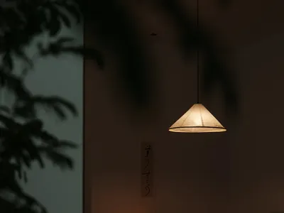 A minimalist cozy lounge area with a paper lampshade, candles, and a traditional Japanese writing scroll hanging on the wall.