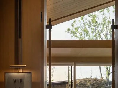 A modern hotel lobby featuring glass walls and a serene outdoor view.