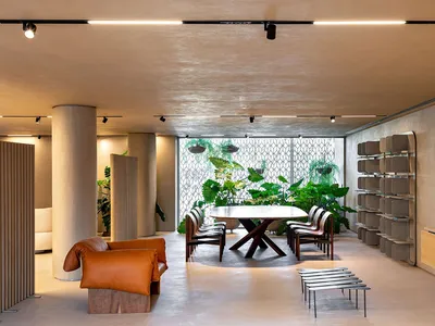 Modern cafe interior with concrete and natural materials, featuring industrial-style furniture and greenery.