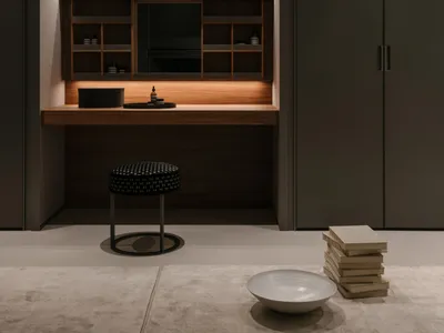 A modern home office with a wooden desk, glass shelves, and leather seating.