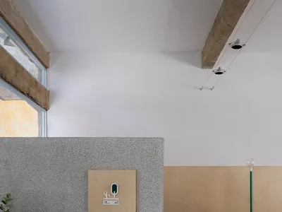 A minimalist restaurant interior featuring a textured concrete counter with green accents.