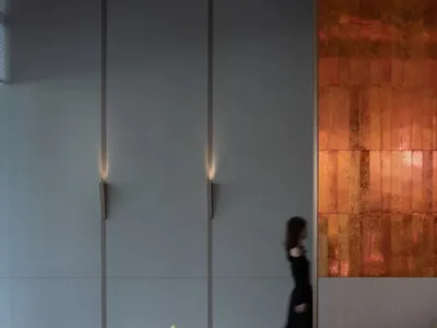 A minimalist restaurant interior featuring metallic tiles, wood, and glass.