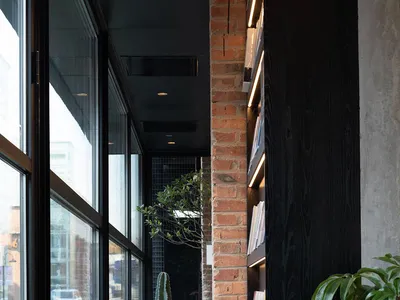 Café interior with a brick wall, concrete columns, and greenery.