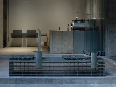 A sleek, modern industrial coffee shop featuring a marble counter and concrete columns.