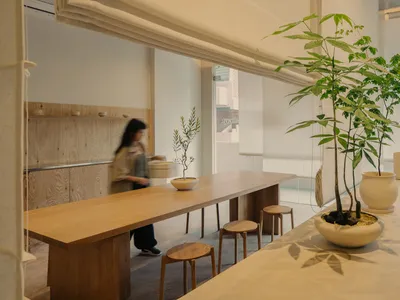 現代餐廳室內設有長木桌與木凳，搭配植栽與極簡設計。