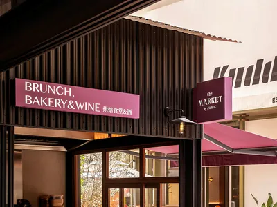 A modern entrance to a brunch bakery, featuring a brick and metal facade with a glass door and awning.