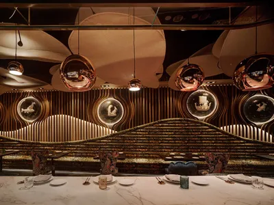 Modern restaurant dining area featuring a combination of copper, glass, and wood materials.