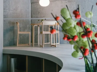 A modern restaurant interior with concrete walls and wooden furniture.