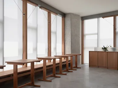 簡約風格的餐廳室內，木質餐桌搭配大型玻璃牆，讓自然光灑滿整個空間。