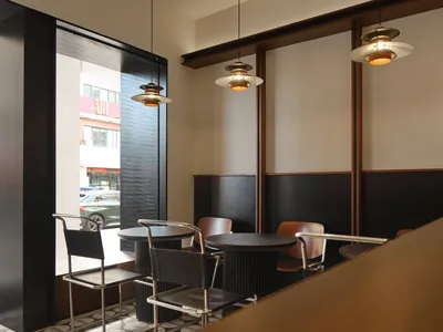 A modern restaurant interior with metallic furniture and concrete walls.