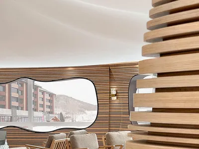 A modern hotel lobby featuring wooden walls and furniture, with a view of snowy mountains through a large window.