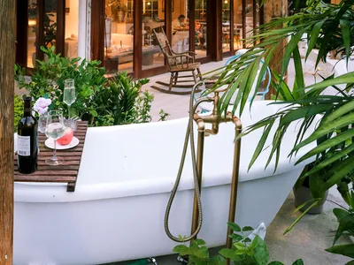 A white ceramic bathtub adorned with green plants and decorative items, set against a backdrop of a cozy indoor space.