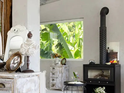 A spacious industrial living room with concrete walls and ceiling, large open windows, and a black stove with a natural wood