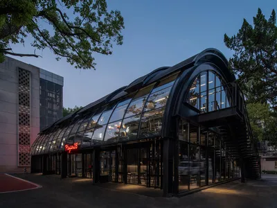 A modern restaurant with a glass exterior featuring black structural elements and a spiral staircase.