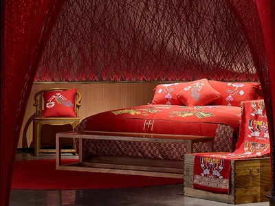 Modern bedroom designed with red fabric, wooden furniture, and geometric patterns.