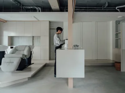 Minimalist living room with concrete floor, white walls, and furniture.