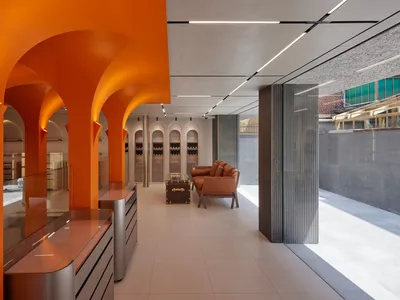 A modern restaurant interior with orange walls and concrete columns.