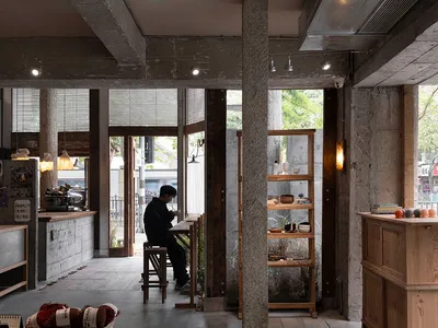 Interior of a coffee shop featuring concrete and wooden materials.